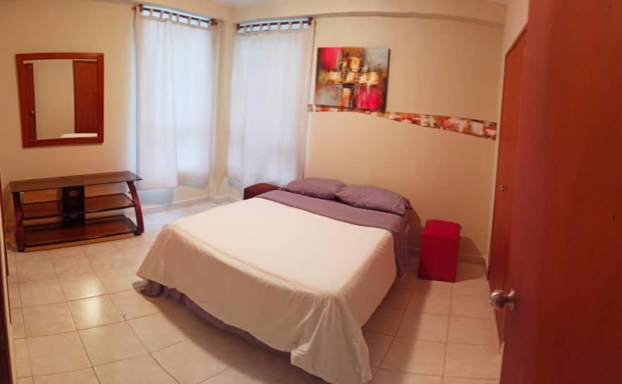 ein kleines Schlafzimmer mit einem Bett und einem Spiegel in der Unterkunft Apartamento con vista al Mar y salida a la playa in Tucacas