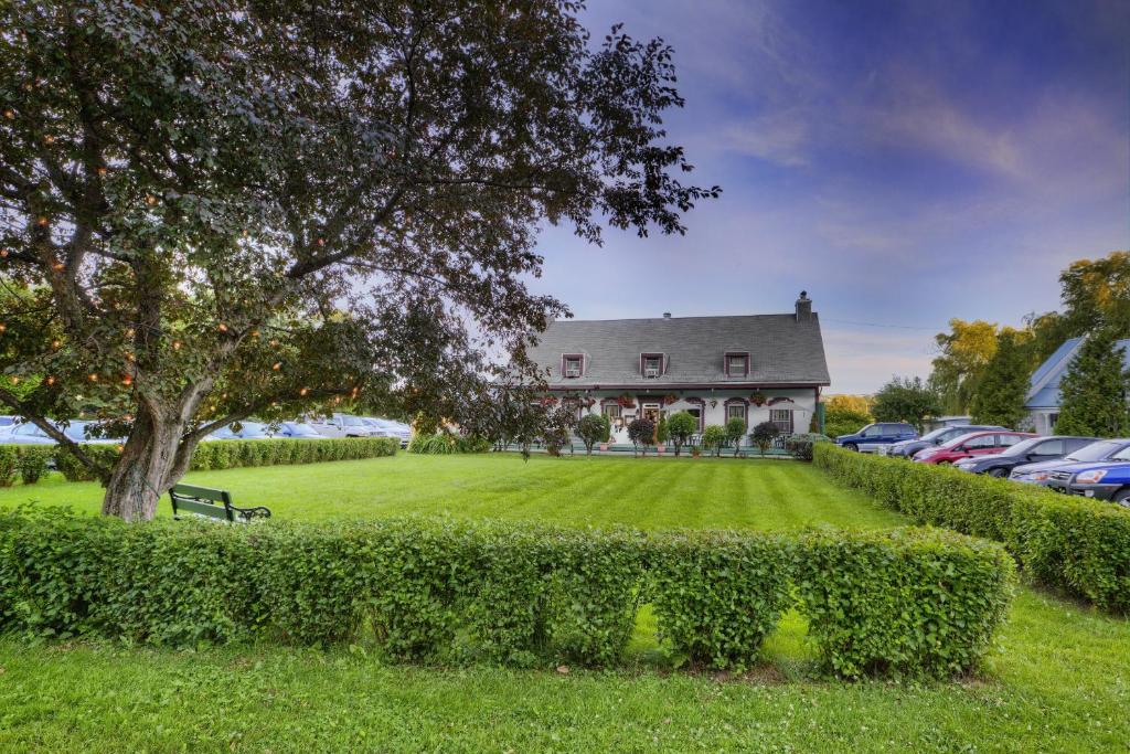 una casa grande con un patio y coches aparcados en Auberge Baker, en Chateau Richer