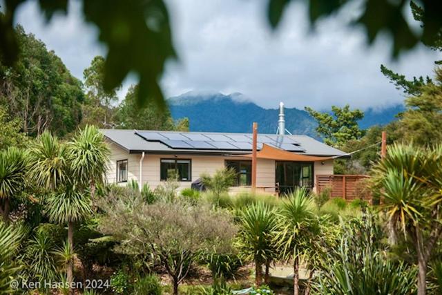 a house with solar panels on top of it at Mill Creek Cottage in Coroglen