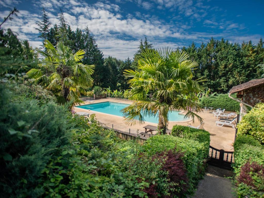 una piscina en un patio con palmeras en Gite Les Terrasses, en Prats-du-Périgord