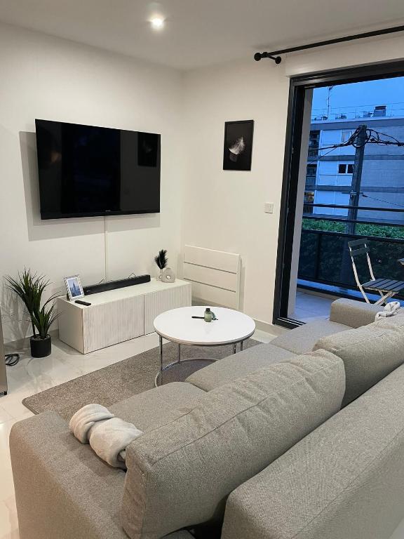 un salon avec un canapé et une télévision dans l'établissement Le Cosy proche Disney, à Vaires-sur-Marne