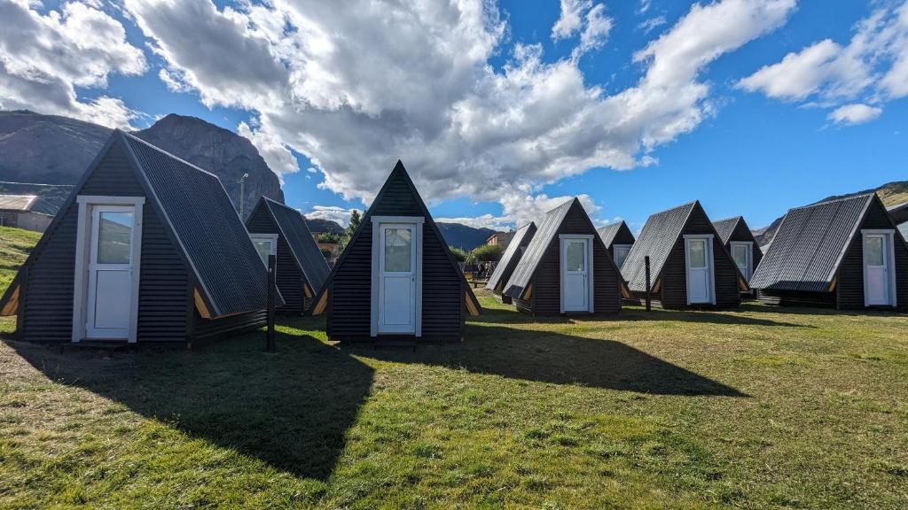 una fila de cabañas en un campo de hierba en Camping El Relincho, en El Chaltén