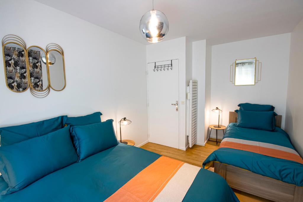 two beds in a bedroom with blue and orange at Appartement cosy aux portes de Paris in Aubervilliers