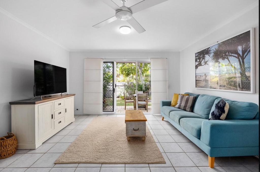 Una sala de estar con un sofá azul y un televisor. en Seychelles 2 - Short stroll to Noosa River, en Noosaville