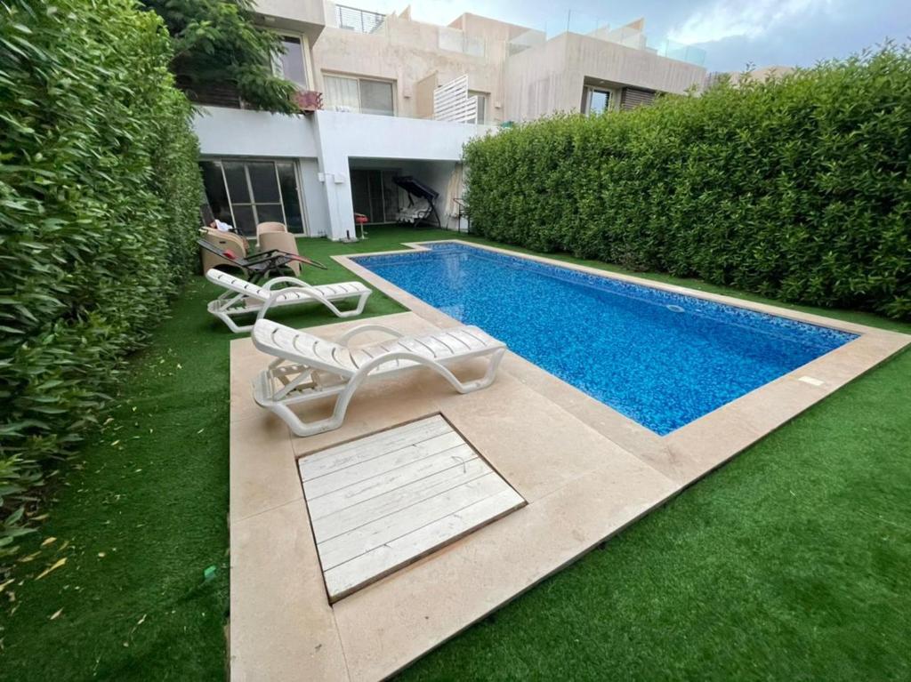 a swimming pool with two lounge chairs next to a house at Hacienda bay standalone in El Alamein