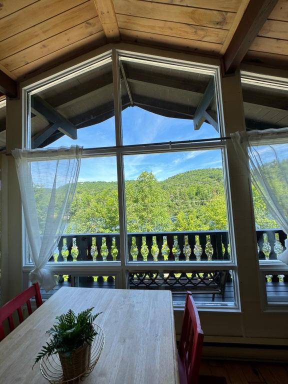 a dining room with a table and a large window at Chalet Alpin Suisse Au Bord Du Lac in Morin Heights