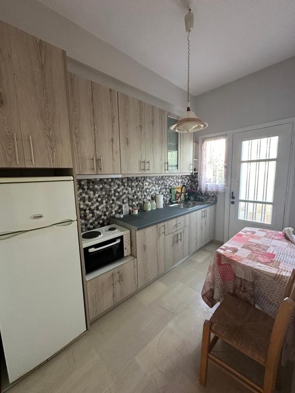 a kitchen with wooden cabinets and a table in it at Γκαρσονιέρα δίπλα στη θάλασσα. in Kómi