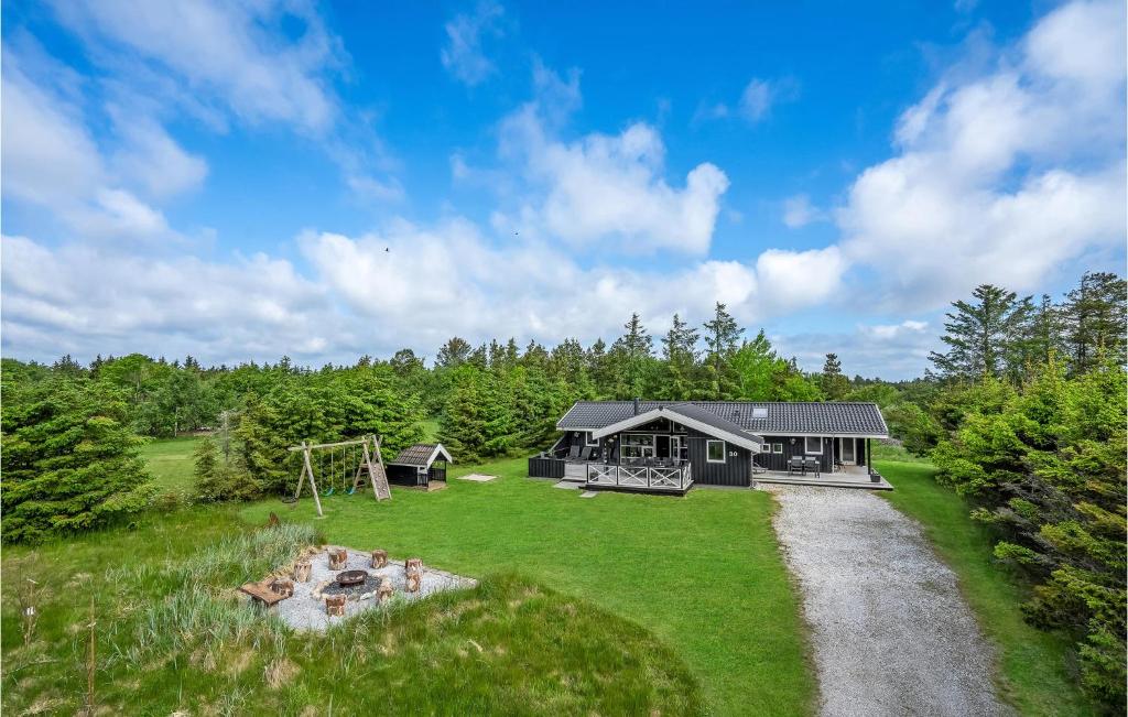 a black house with a playground in the grass at Holiday Home Jægerens Vej in Blokhus
