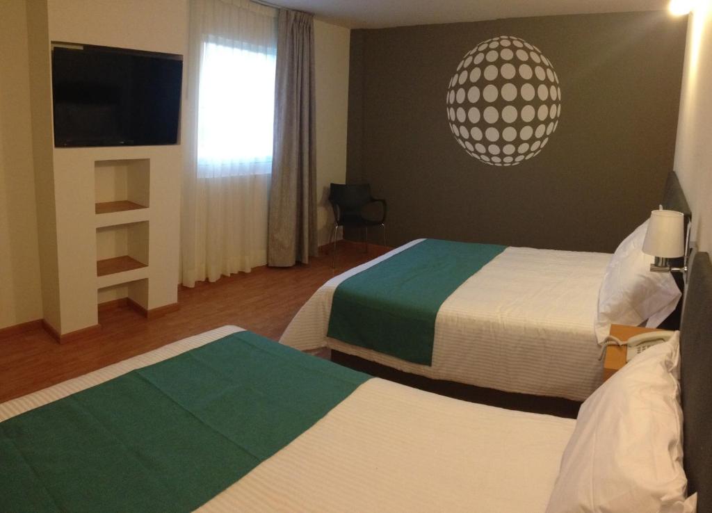 a hotel room with two beds and a flat screen tv at Hotel Dajana Boulevard in Le&oacute;n