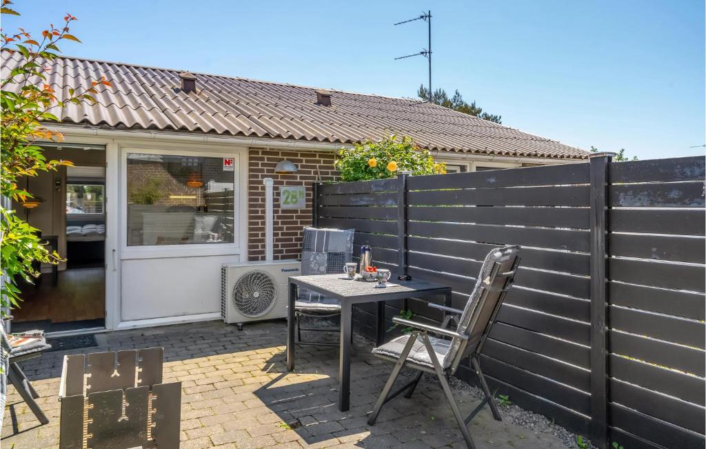 a patio with a table and chairs in front of a fence at Holiday Home Bl in Blåvand