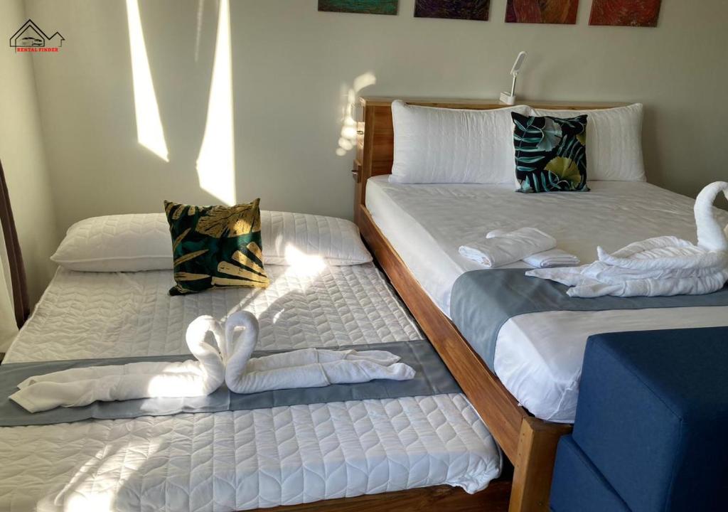 two beds with swans made out of towels on them at Affordable Group Stay with a Balcony, Free Parking, Pool and Gym - B2 7Opals in Puerto Princesa City