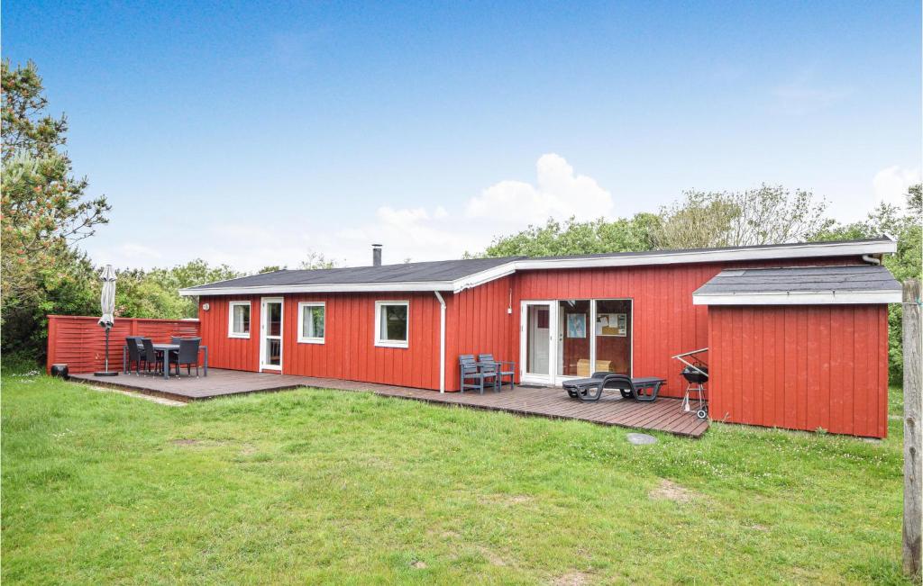 a red house with a deck in a yard at Alsbo in Sønderho