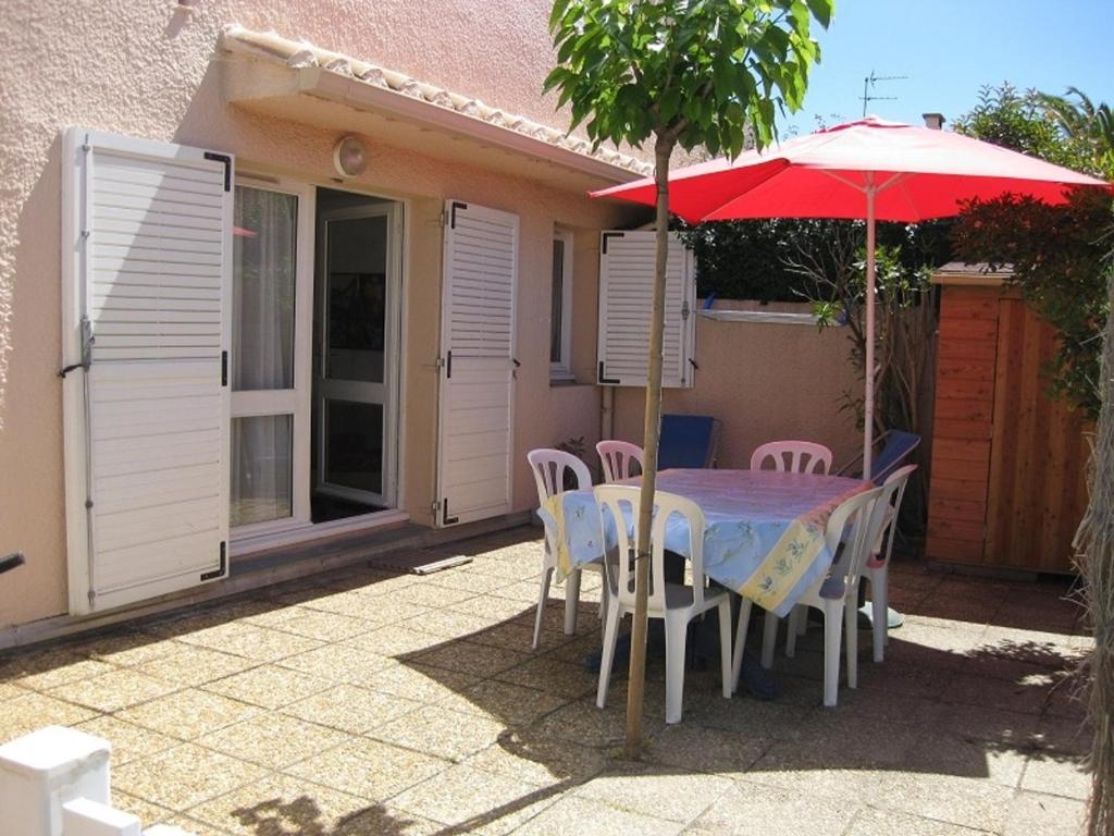 une table, des chaises et un parasol en face d'une maison dans l'établissement Saint-Cyprien: T3 en RDC, Terrasse, Parking, à 600m de la Plage - FR-1-793-15, à Saint-Cyprien