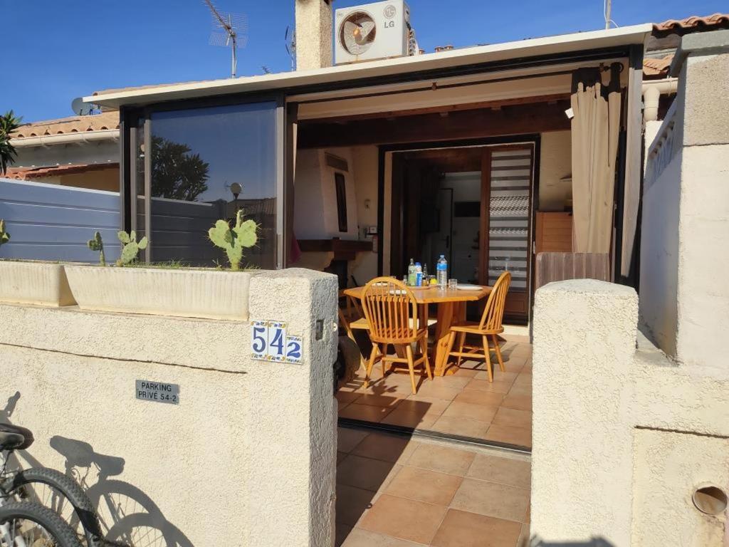 une maison avec une table et des chaises sur une terrasse dans l'établissement Villa Climatisée Proche Plage, Idéale Famille, Parking Privé, Lave-linge, Lave-vaisselle - FR-1-796-27, à Gruissan