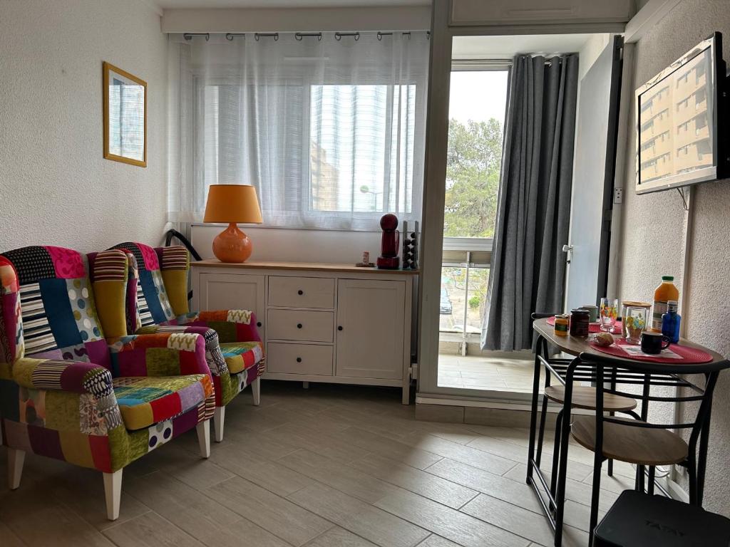 un salon avec un canapé, une table et une fenêtre dans l'établissement Studio Climatisé pour 2 Pers avec Loggia & Parking à 200m de la Plage à Saint-Cyprien - FR-1-793-18, à Saint-Cyprien