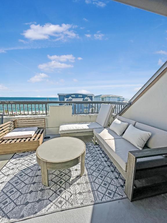 a balcony with a couch and a table and the ocean at Beach Paradise - Perfect Ocean Sunset Views with Pool & Sauna & Breakfast! in Mexico Beach