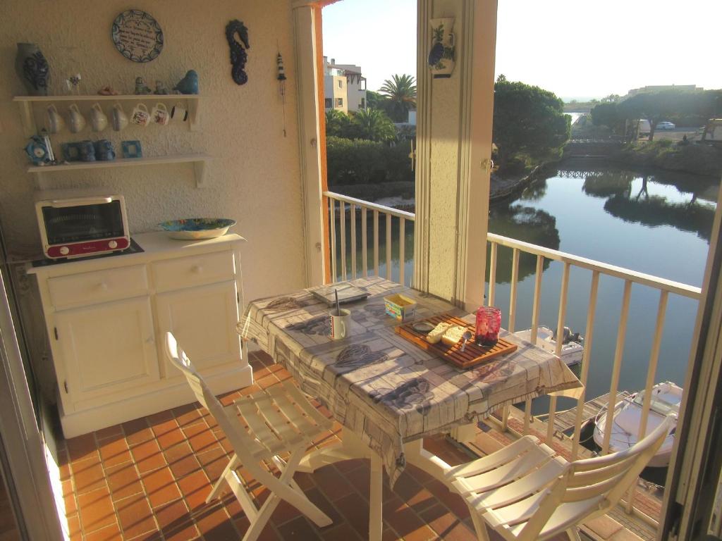 une table et des chaises sur un balcon avec vue sur l'eau dans l'établissement Saint Cyprien T2 Mezzanine 4P avec Parking, Belle vue Lagune et Mer - FR-1-793-11, à Saint-Cyprien