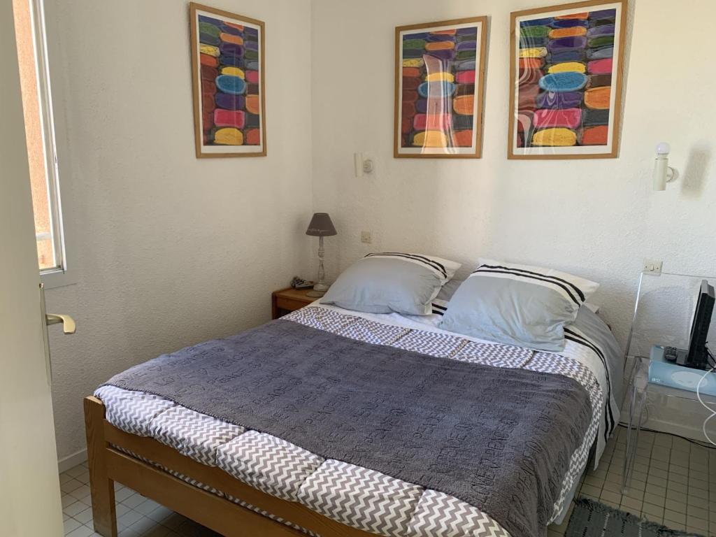un lit dans une chambre avec deux tableaux au mur dans l'établissement T2 40m² à 150m de la plage avec parking privé et loggia - Gruissan - FR-1-796-26, à Gruissan