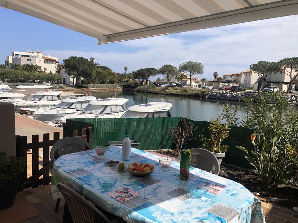 une table avec un bol de fruits sur une terrasse avec des bateaux dans l'établissement Studio Alcôve 4 Pers RDC avec Parking Privé et Animaux admis à Saint-Cyprien - FR-1-793-24, à Saint-Cyprien