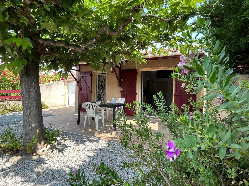 un patio avec une table et des chaises sous un arbre dans l'établissement Villa T4 mezzanine climatisée avec parking, proche plage et port à Saint-Cyprien - FR-1-793-28, à Saint-Cyprien
