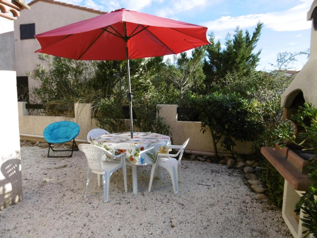 une table et des chaises avec un parasol rouge dans l'établissement Charmante Villa T3 - 5 Pers - Proche Plage et Port - Saint Cyprien - FR-1-793-30, à Saint-Cyprien
