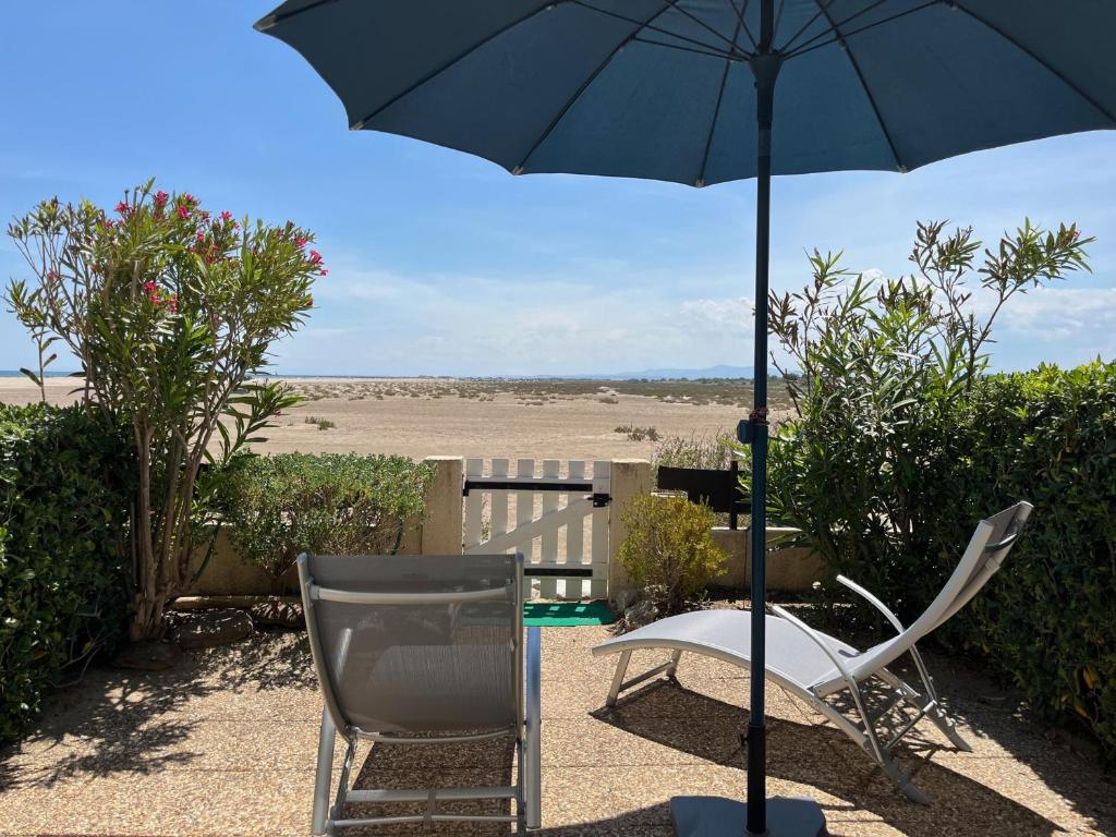 une chaise et un parasol à côté d'une chaise et d'une table dans l'établissement Direct Plage, Piscine et Parking - Confort Moderne pour 4 Pers - FR-1-796-37, à Gruissan