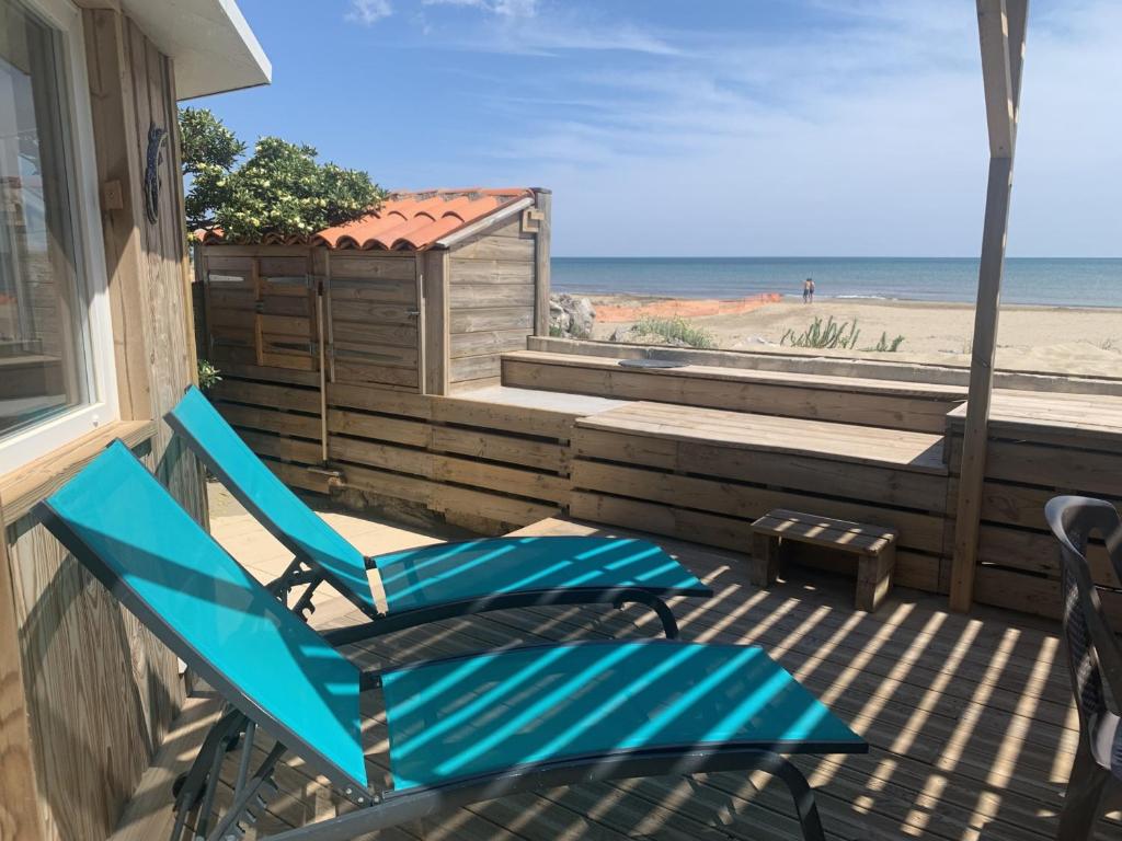 une paire de chaises bleues sur un porche avec la plage dans l'établissement Gruissan, T3 climatisé sur plage, terrasse, 4 pers - FR-1-796-68, à Gruissan