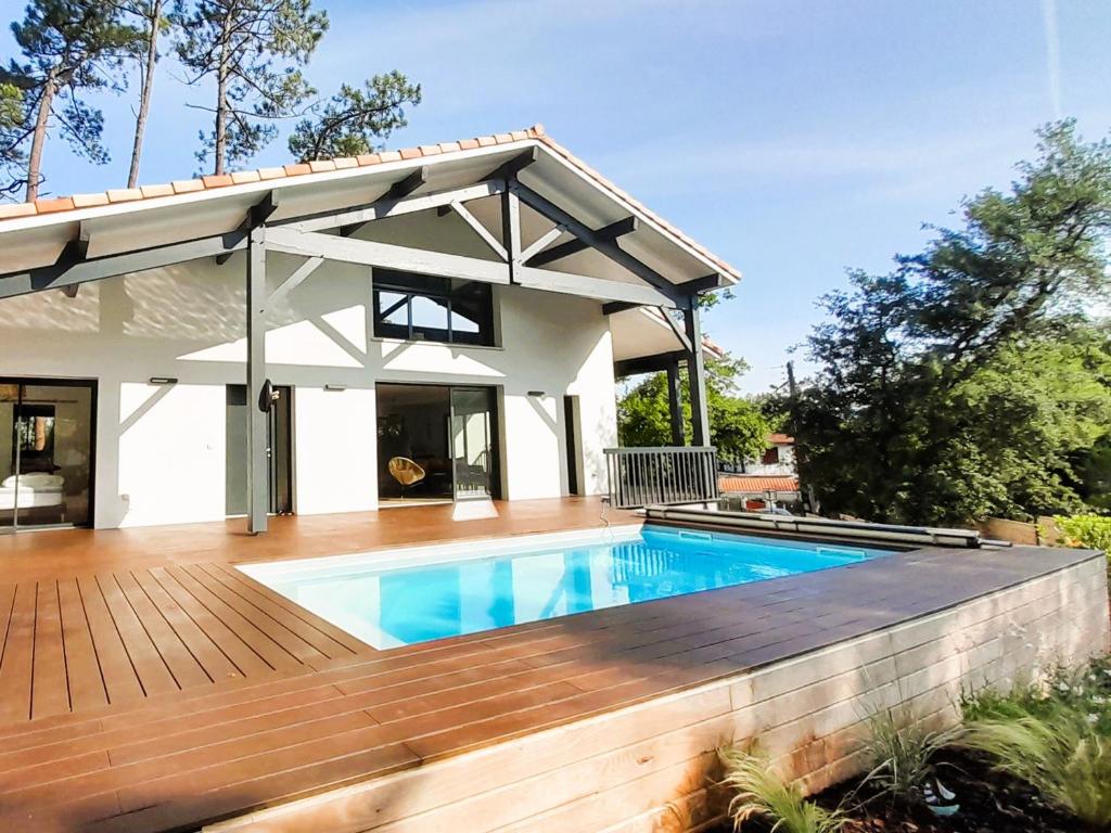une maison avec une piscine et une terrasse en bois dans l'établissement Villa de Prestige avec Piscine Chauffée, Proche Plages et Port de Capbreton - FR-1-239-1070, à Capbreton