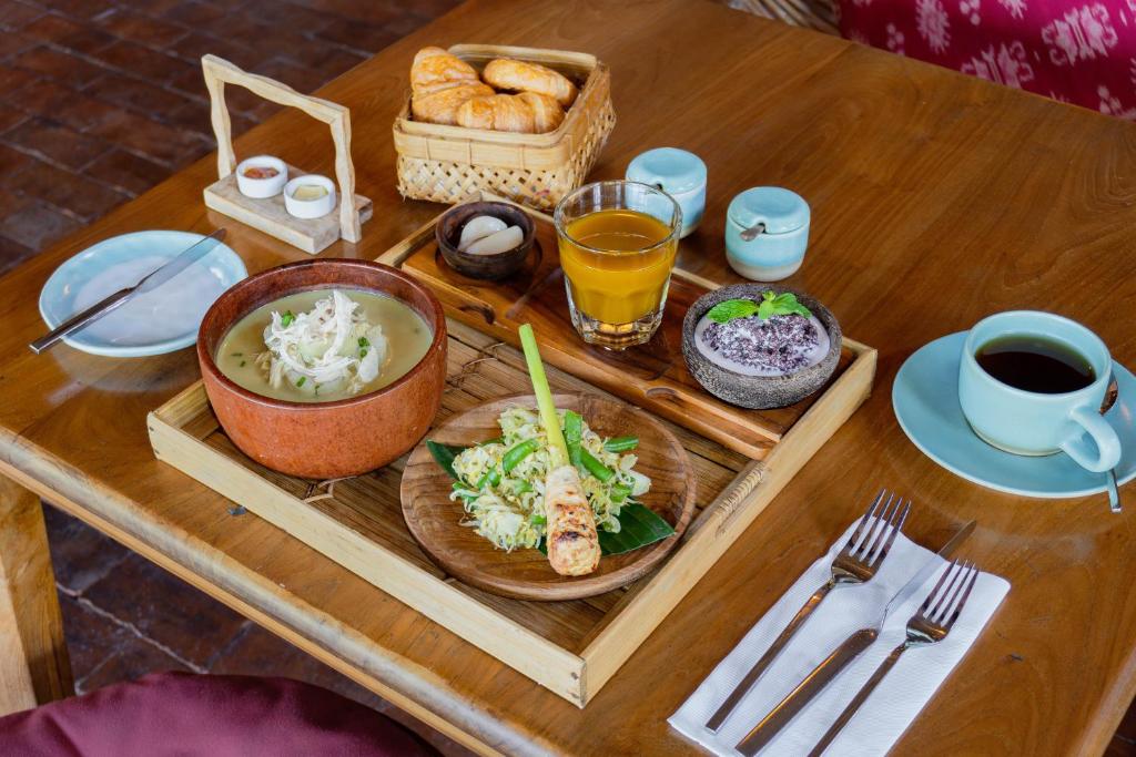 a wooden table with a tray of food on it at Amnaya Resort Kuta in Kuta