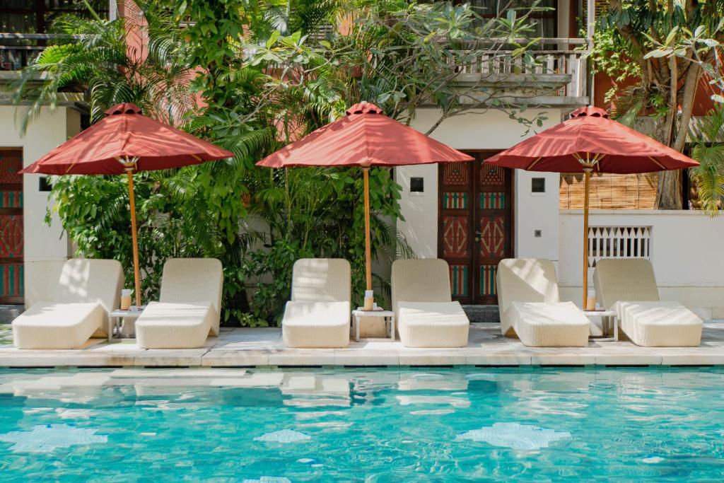 a group of chairs and umbrellas next to a swimming pool at Amnaya Resort Kuta in Kuta