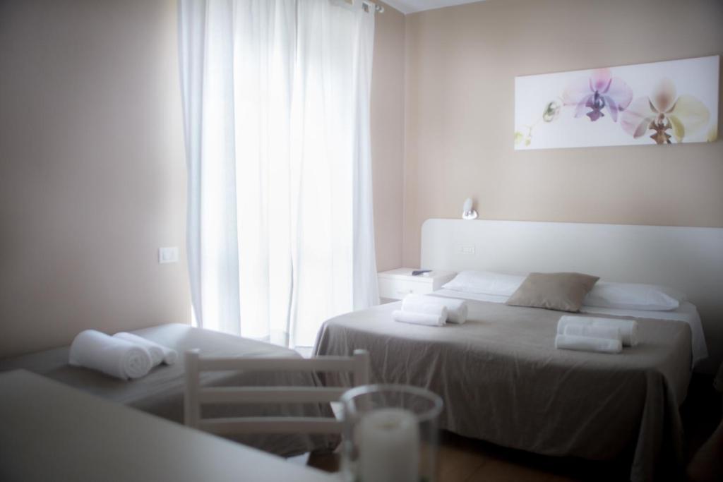 a white room with two beds and a window at Anna Guest House in Rome
