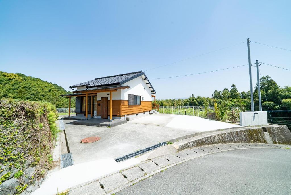 una pequeña casa con entrada junto a una carretera en 妹川ロッジ, en Kugumiya