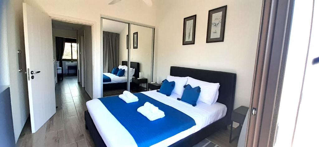 a bedroom with a blue and white bed and a mirror at Queens Gardens Bliss in Paphos City