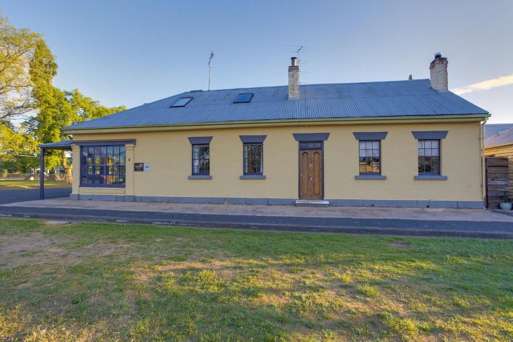 a yellow building with a door and a grass field at Whites Corner in Bothwell