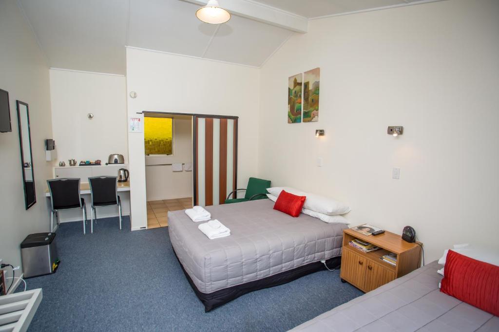 - une chambre avec un lit blanc, une table et des chaises dans l'établissement The Coast Motel, à Timaru