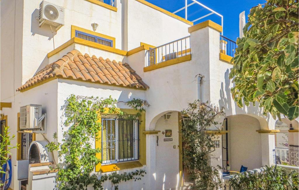 a white house with a yellow door and trees at Urb Al Andalus I in Villamartin