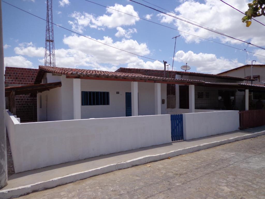 a white house with a white fence next to a street at Casa Mobiliada Galinhos in Galinhos