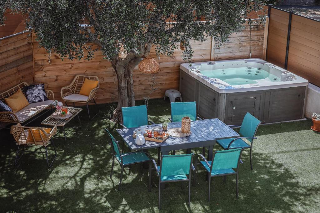 un patio avec une table et des chaises et un bain à remous dans l'établissement La Rêveuse - VILLA PAULA, à Istres