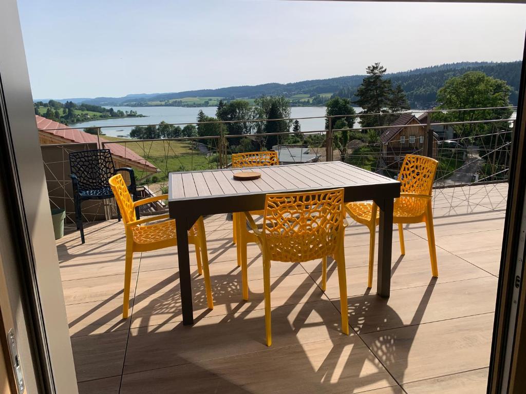 une table et des chaises sur un balcon avec vue sur l'eau dans l'établissement Vue lac, à Montperreux