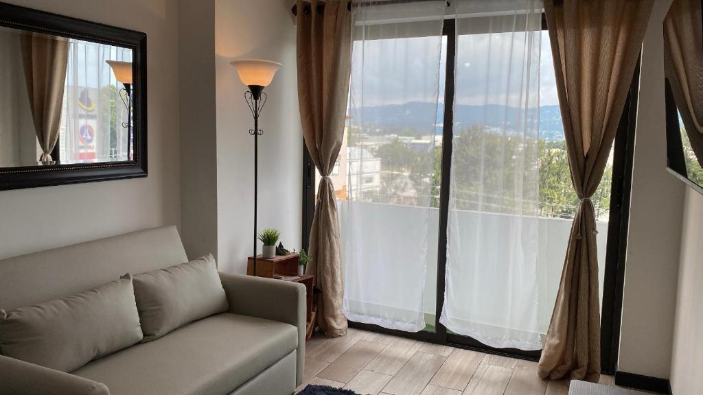 a living room with a couch and a large window at Apartamento Centro de la Ciudad de Guatemala, zona 12 Edificio Petapolis in Guatemala