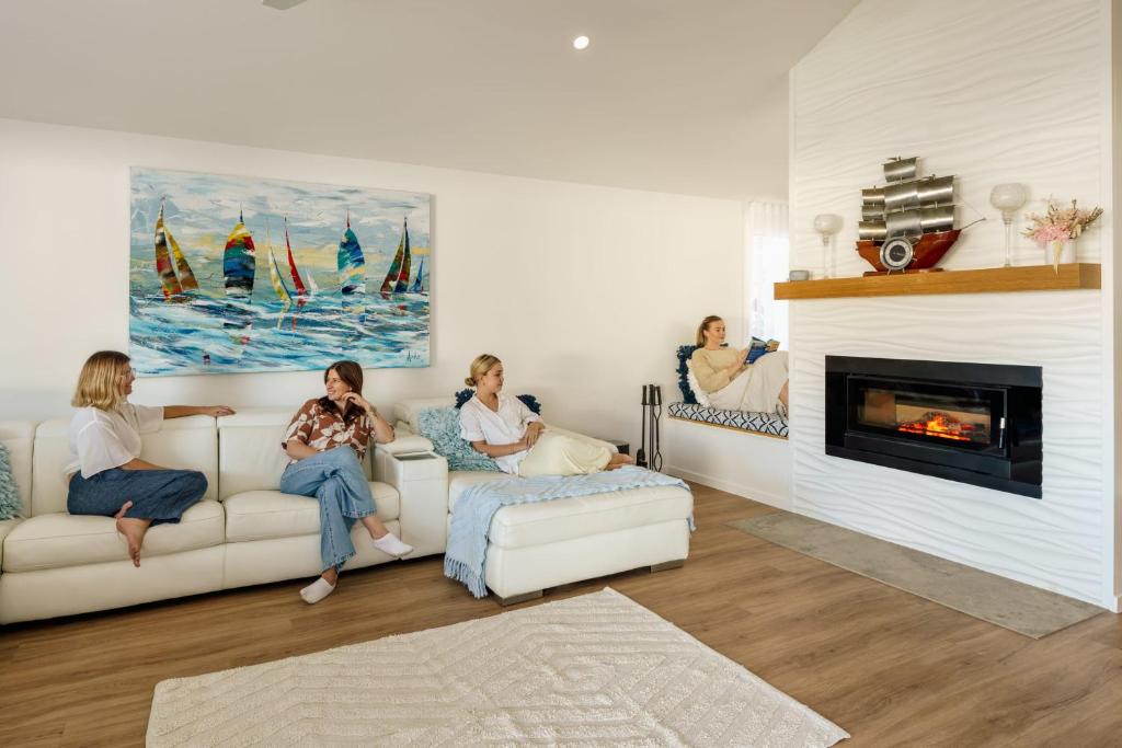 three women sitting on a couch in a living room with a fireplace at Golden Beach Ultimate Family Getaway - Pool & Spa in Golden Beach