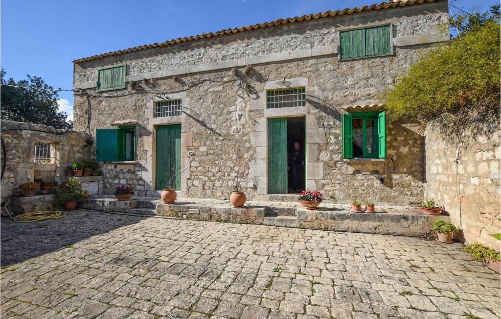 a stone house with green windows and a stone driveway at Beautiful Home In Rosolini With Wifi in Rosolini