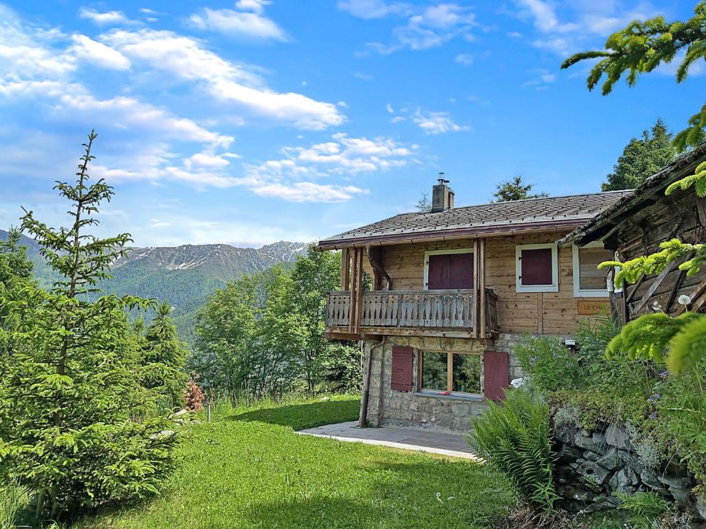 a log house with a deck and mountains in the background at Chalet a Didi - Alps Paradise - 4 Vallees in La Tzoumaz
