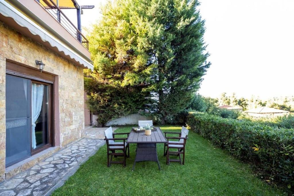 eine Terrasse mit einem Tisch und Stühlen auf dem Rasen in der Unterkunft Sani Pinecone Villa 3 in Sani Beach