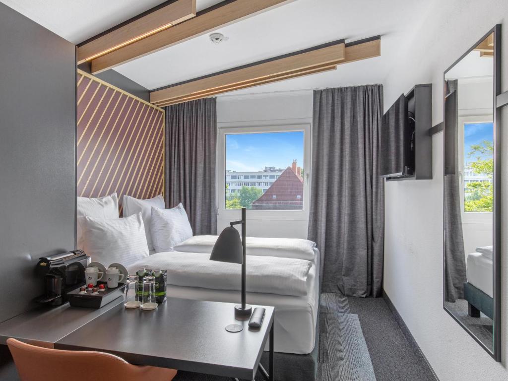 a hotel room with a bed and a desk and a window at B&B Hotel Hamburg-Airport in Hamburg