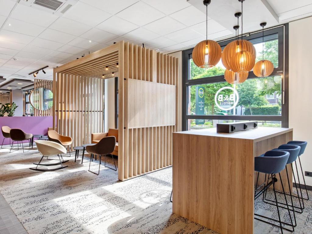 a lobby of a restaurant with a bar and chairs at B&B Hotel Hamburg-Airport in Hamburg