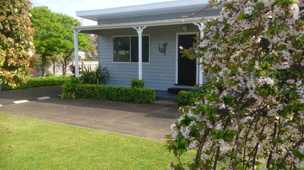 une maison blanche avec des fleurs roses devant elle dans l'établissement Phillip Island Cottages, à Cowes
