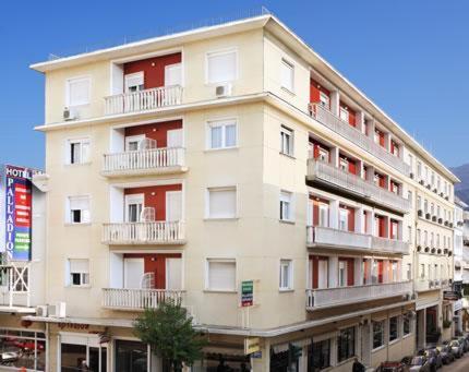 a tall white building with red windows and balconies at Palladion Hotel in Ioannina