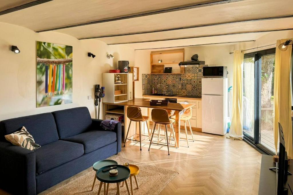 un salon avec un canapé bleu et une cuisine dans l'établissement Escapade au fond du jardin, à Saulce-sur-Rhône