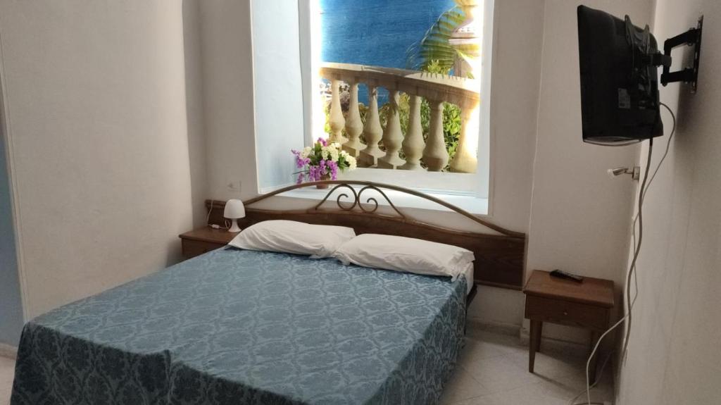 a bedroom with a blue bed and a window at On The Beach SORRENTO in Massa Lubrense